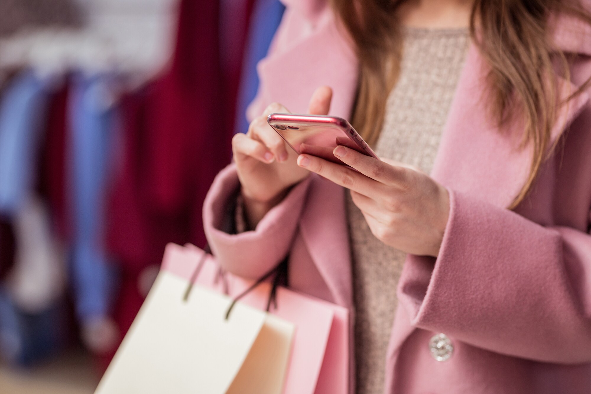 Eine Frau tippt beim Shopping auf ihrem Smartphone.